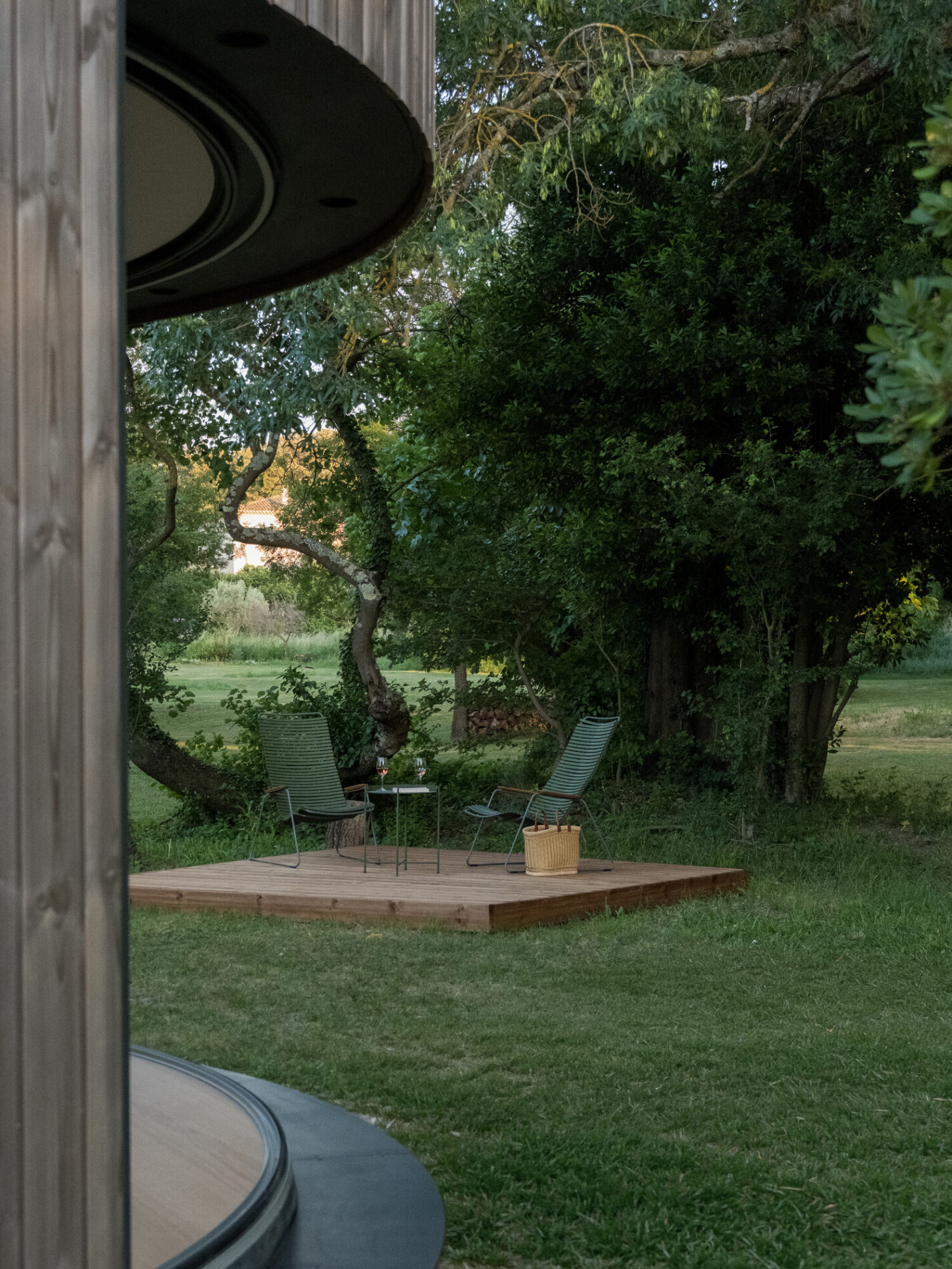 Terrasse privée d'un Lumipod 5 avec deux fauteuils, sous les arbres du parc du Château de Massillan
